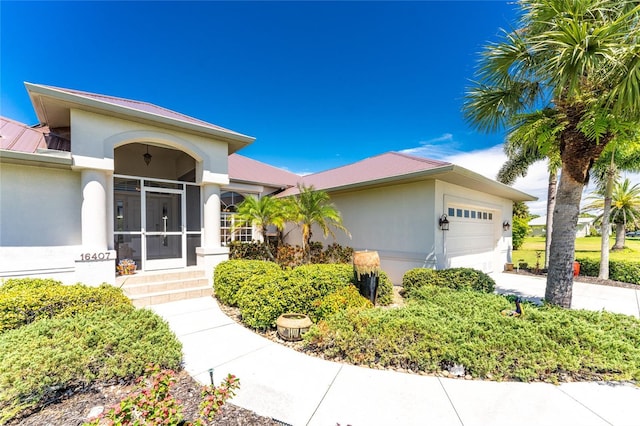 16407 San Edmundo Rd, Punta Gorda, FL 33955 - single story home with stucco siding, an attached garage, a metal roof, and entry steps