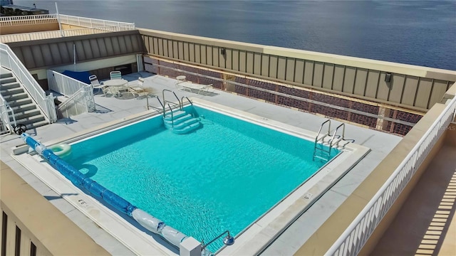 view of pool featuring a patio and a water view