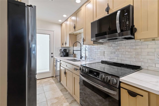 kitchen featuring light brown cabinetry, sink, tasteful backsplash, light stone counters, and stainless steel appliances