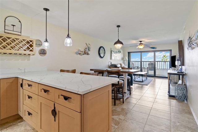 kitchen with decorative light fixtures, light stone counters, light tile patterned floors, and kitchen peninsula