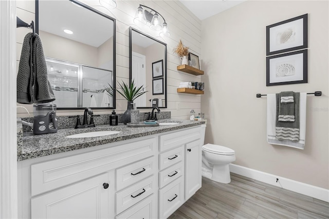 bathroom featuring wood-type flooring, a shower with door, vanity, and toilet