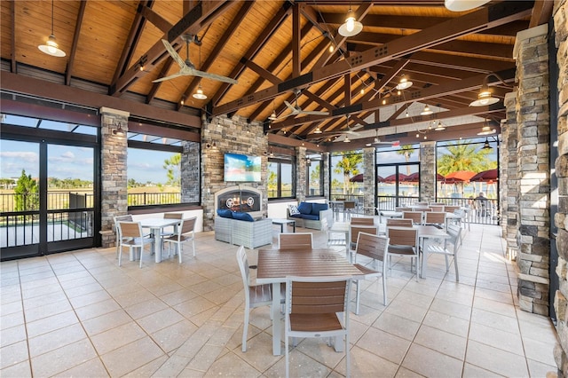 dining room with wooden ceiling, an outdoor stone fireplace, and high vaulted ceiling