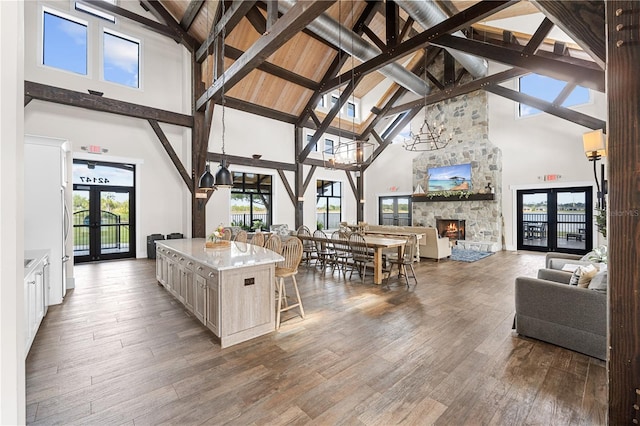 kitchen with high vaulted ceiling, a center island, a fireplace, and french doors