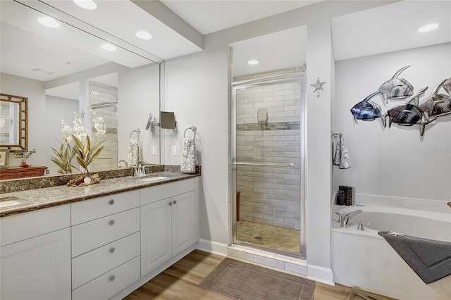 bathroom with vanity, hardwood / wood-style floors, and plus walk in shower