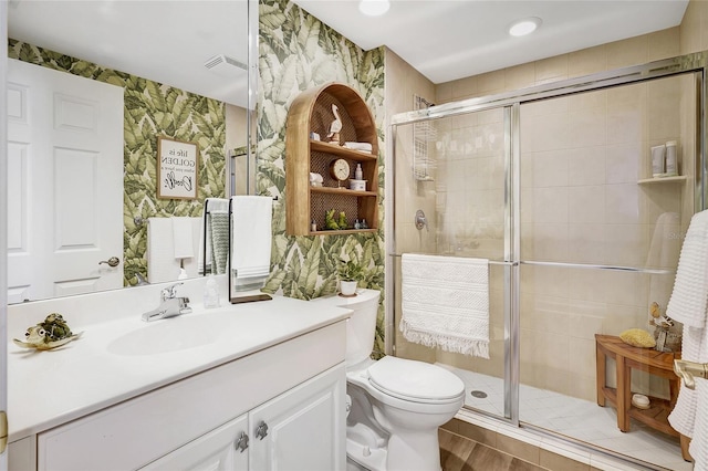 bathroom featuring vanity, toilet, and a shower with shower door