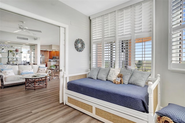 bedroom featuring light wood-type flooring, ceiling fan, and stainless steel refrigerator