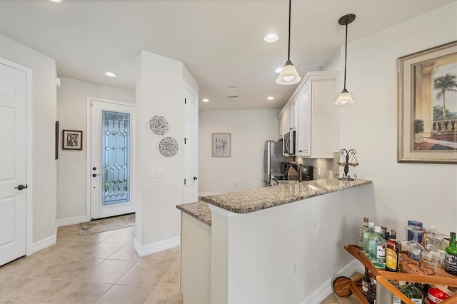 kitchen featuring white cabinetry, kitchen peninsula, hanging light fixtures, stainless steel appliances, and light stone countertops