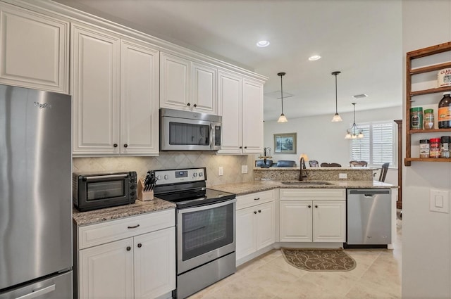 kitchen with stainless steel appliances, white cabinetry, kitchen peninsula, and sink