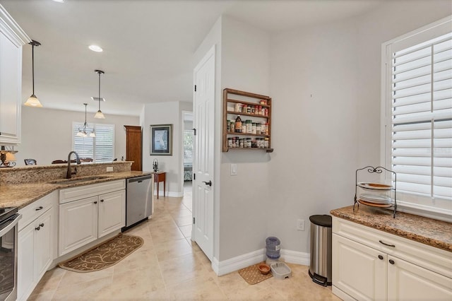 kitchen featuring hanging light fixtures, dark stone countertops, white cabinetry, stainless steel appliances, and sink