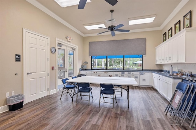 kitchen with dark hardwood / wood-style floors, white cabinetry, a skylight, crown molding, and ceiling fan