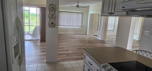 kitchen featuring white refrigerator with ice dispenser, light tile patterned floors, ceiling fan, and range