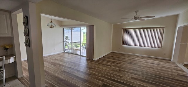 interior space with lofted ceiling, dark hardwood / wood-style flooring, and ceiling fan with notable chandelier