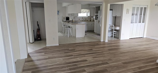 kitchen with white refrigerator with ice dispenser, a kitchen breakfast bar, sink, decorative backsplash, and dark hardwood / wood-style flooring