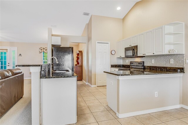 kitchen featuring light tile patterned flooring, white cabinets, kitchen peninsula, black appliances, and dark stone countertops