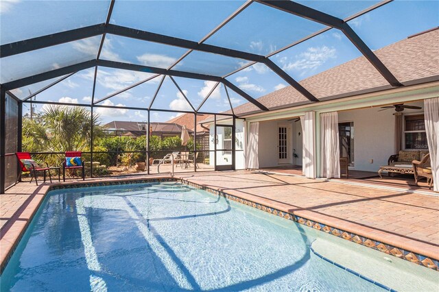 view of pool with a patio, glass enclosure, and ceiling fan