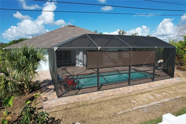 view of pool with glass enclosure and a patio