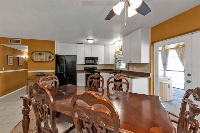 tiled dining space featuring a textured ceiling, sink, and ceiling fan