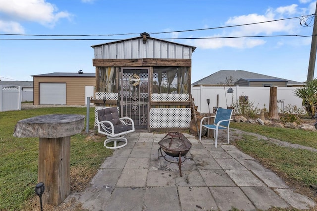 view of patio / terrace with a garage, an outdoor fire pit, and an outbuilding