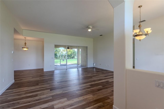 spare room with ceiling fan with notable chandelier and dark hardwood / wood-style flooring