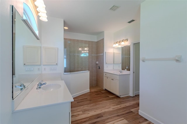 bathroom featuring wood-type flooring, vanity, and tiled shower