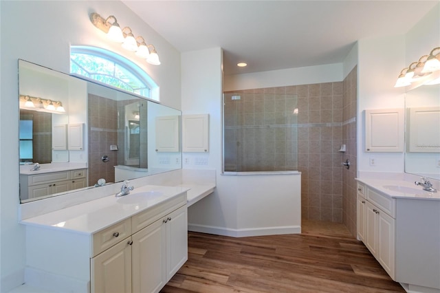 bathroom with wood-type flooring, vanity, and a tile shower