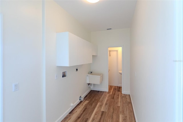 laundry room with sink, cabinets, hookup for a washing machine, light hardwood / wood-style floors, and electric dryer hookup