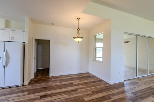 kitchen with white fridge with ice dispenser, dark hardwood / wood-style flooring, pendant lighting, and white cabinets