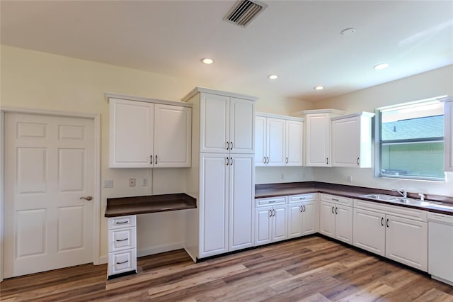 kitchen featuring light hardwood / wood-style flooring, white cabinets, white dishwasher, and sink