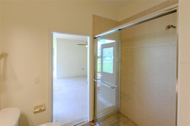 bathroom with ceiling fan, an enclosed shower, and toilet