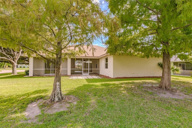 rear view of house featuring a lawn, a sunroom, and a patio area