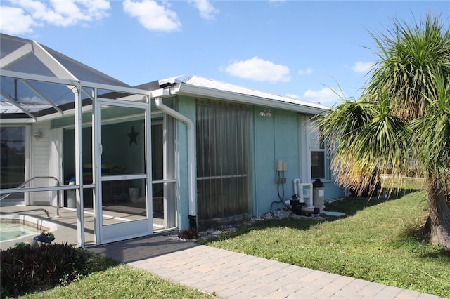 view of side of home featuring glass enclosure, a patio area, and a lawn