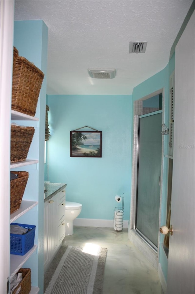 bathroom with a shower with door, vanity, toilet, and a textured ceiling