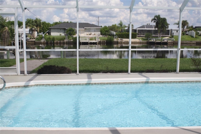 view of swimming pool with a yard, glass enclosure, and a water view