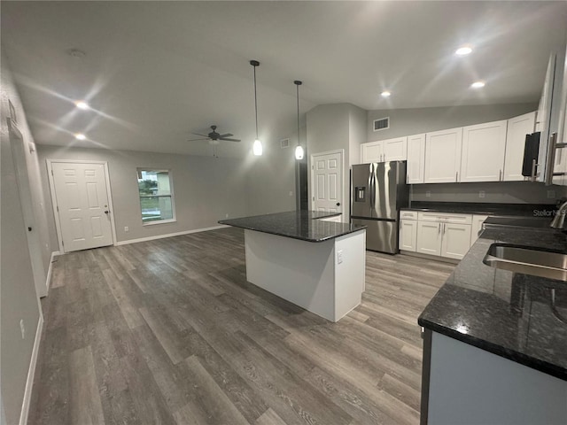 kitchen with white cabinetry, sink, pendant lighting, dark stone counters, and stainless steel fridge