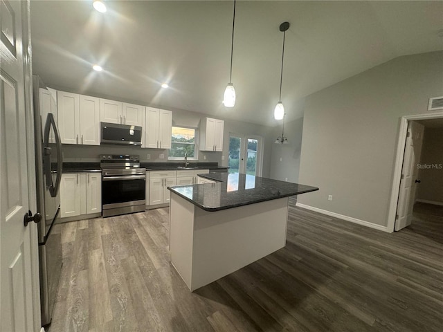 kitchen featuring white cabinets, pendant lighting, lofted ceiling, and appliances with stainless steel finishes