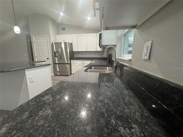 kitchen featuring white cabinetry, stainless steel refrigerator with ice dispenser, sink, pendant lighting, and dark stone counters