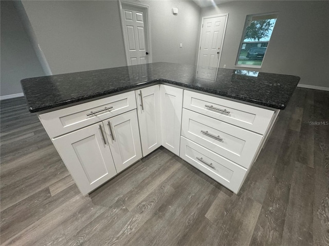 kitchen featuring white cabinets, dark stone counters, and dark hardwood / wood-style floors