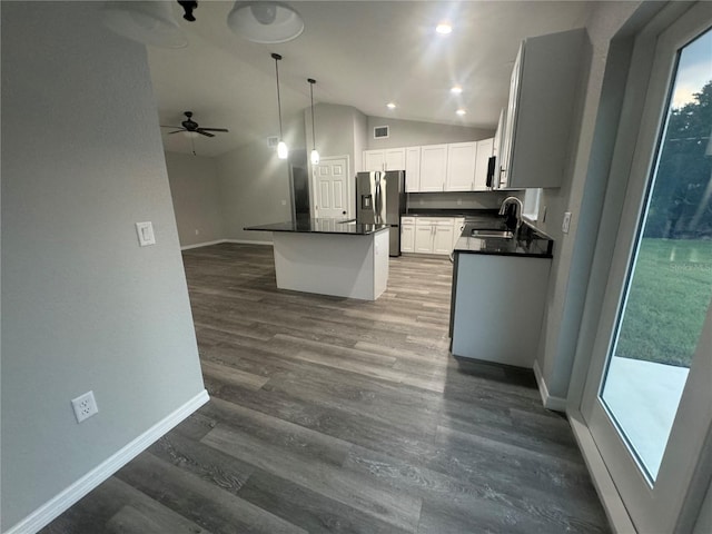 kitchen with pendant lighting, stainless steel fridge, sink, white cabinets, and lofted ceiling