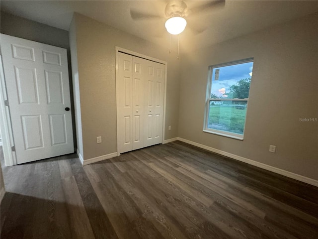 unfurnished bedroom with dark hardwood / wood-style floors, a closet, and ceiling fan