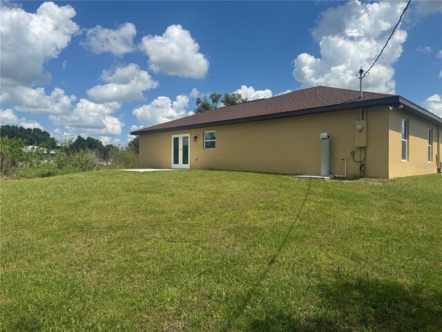 back of house with french doors and a lawn