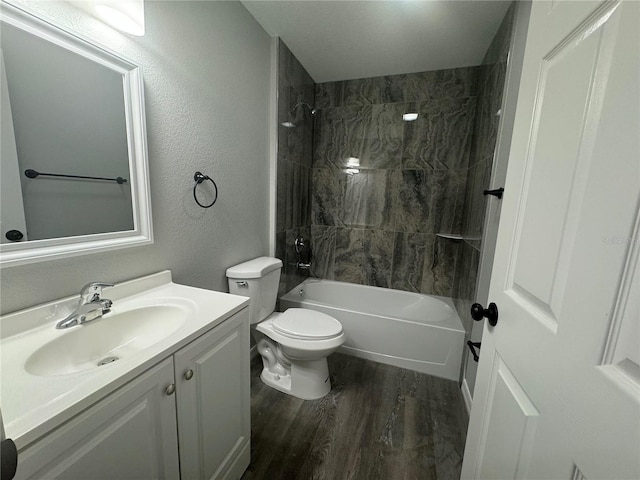 full bathroom featuring vanity, hardwood / wood-style flooring, tiled shower / bath, and toilet