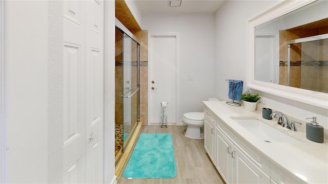 bathroom with hardwood / wood-style floors, vanity, a shower with shower door, and toilet