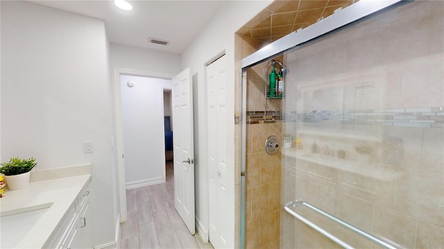 bathroom featuring a shower with door and vanity