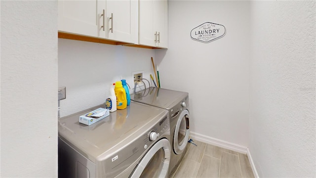 clothes washing area featuring washer and clothes dryer and cabinets