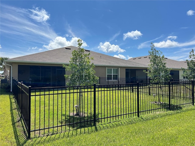 view of front of home featuring a front yard, a sunroom, a fenced backyard, and stucco siding