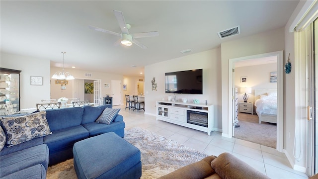 living room featuring ceiling fan with notable chandelier, visible vents, baseboards, and light tile patterned floors