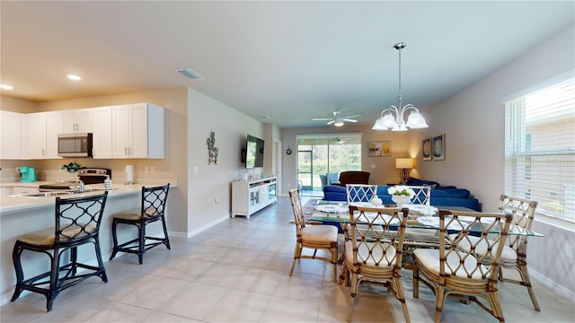 tiled dining area featuring ceiling fan with notable chandelier and sink