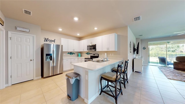 kitchen featuring a peninsula, appliances with stainless steel finishes, a sink, and visible vents