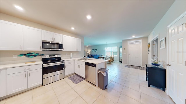 kitchen featuring a peninsula, white cabinets, open floor plan, light countertops, and appliances with stainless steel finishes