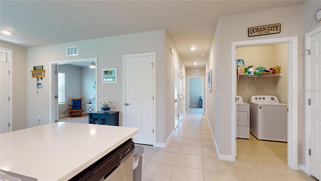 kitchen with light tile patterned floors, a center island, separate washer and dryer, and stainless steel dishwasher